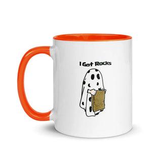 a white and orange coffee mug with a cartoon of a ghost holding a piece of